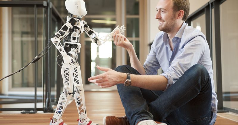 photographie d'un homme travaillant avec un robot poppy